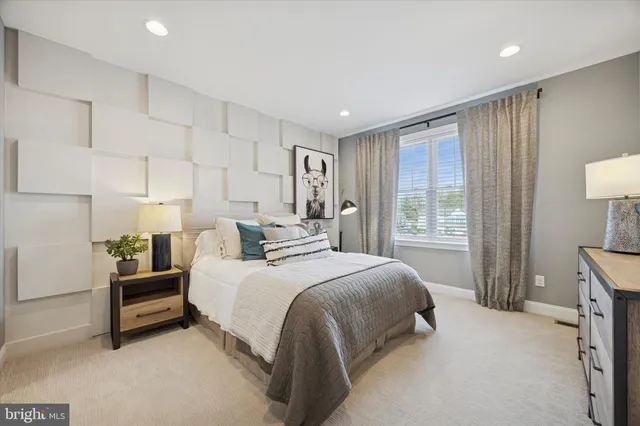 a spacious bedroom with two bed and a lamp on dresser