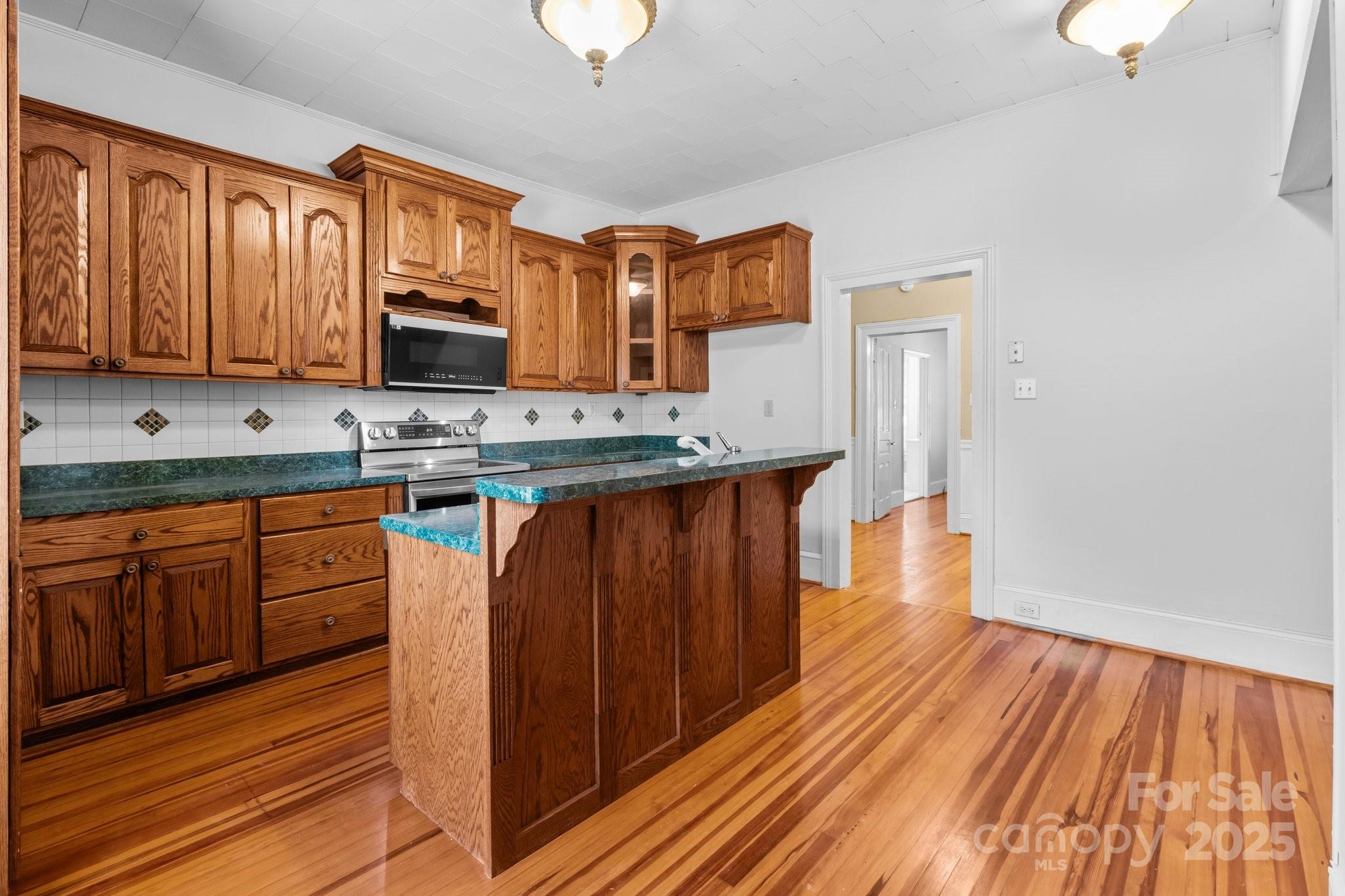 405 7th Street Spencer, NC 28159 - Photo 19 of 39 a kitchen with stainless steel appliances granite countertop a sink stove and wooden floor