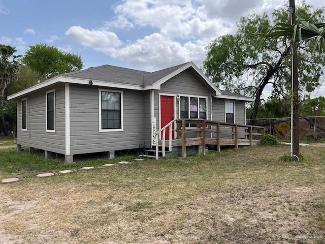 View of front of house featuring a front lawn and a deck