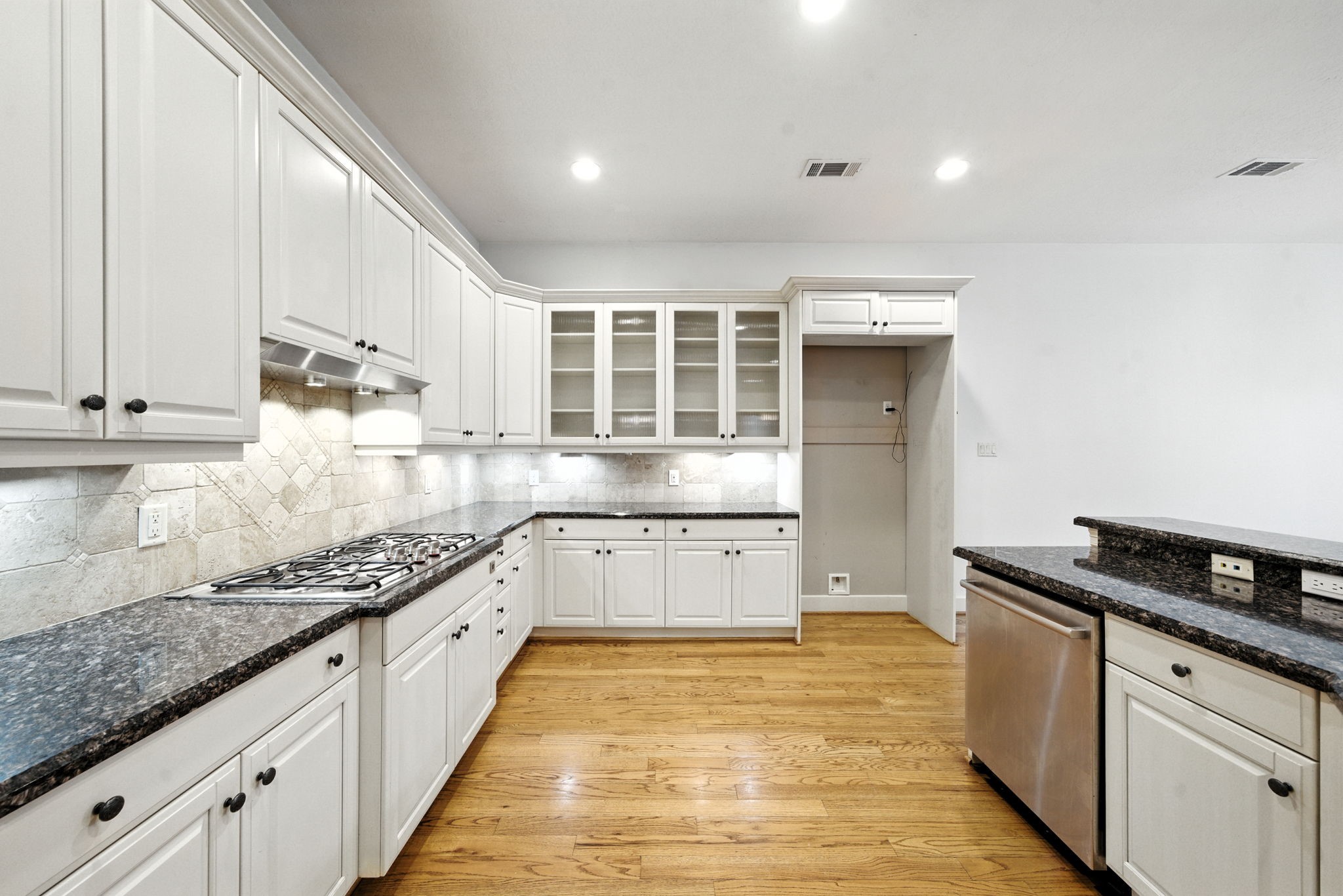 2714 Stuart Manor Houston, TX 77082 - Photo 18 of 49 Glass-front cabinets, a gas cooktop, and abundant counter space give this kitchen a timeless and practical appeal. Whether preparing meals or hosting gatherings, this space blends elegance with everyday convenience.