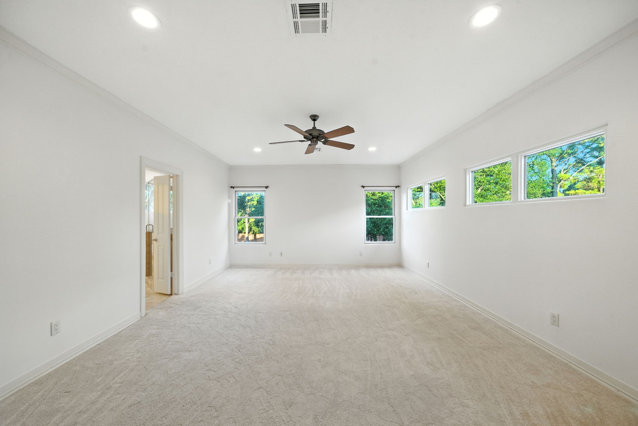 2714 Stuart Manor Houston, TX 77082 - Photo 26 of 49 The spacious primary bedroom impresses with soaring ceilings, recessed lighting, and a wall of windows that invite in natural light while maintaining privacy.