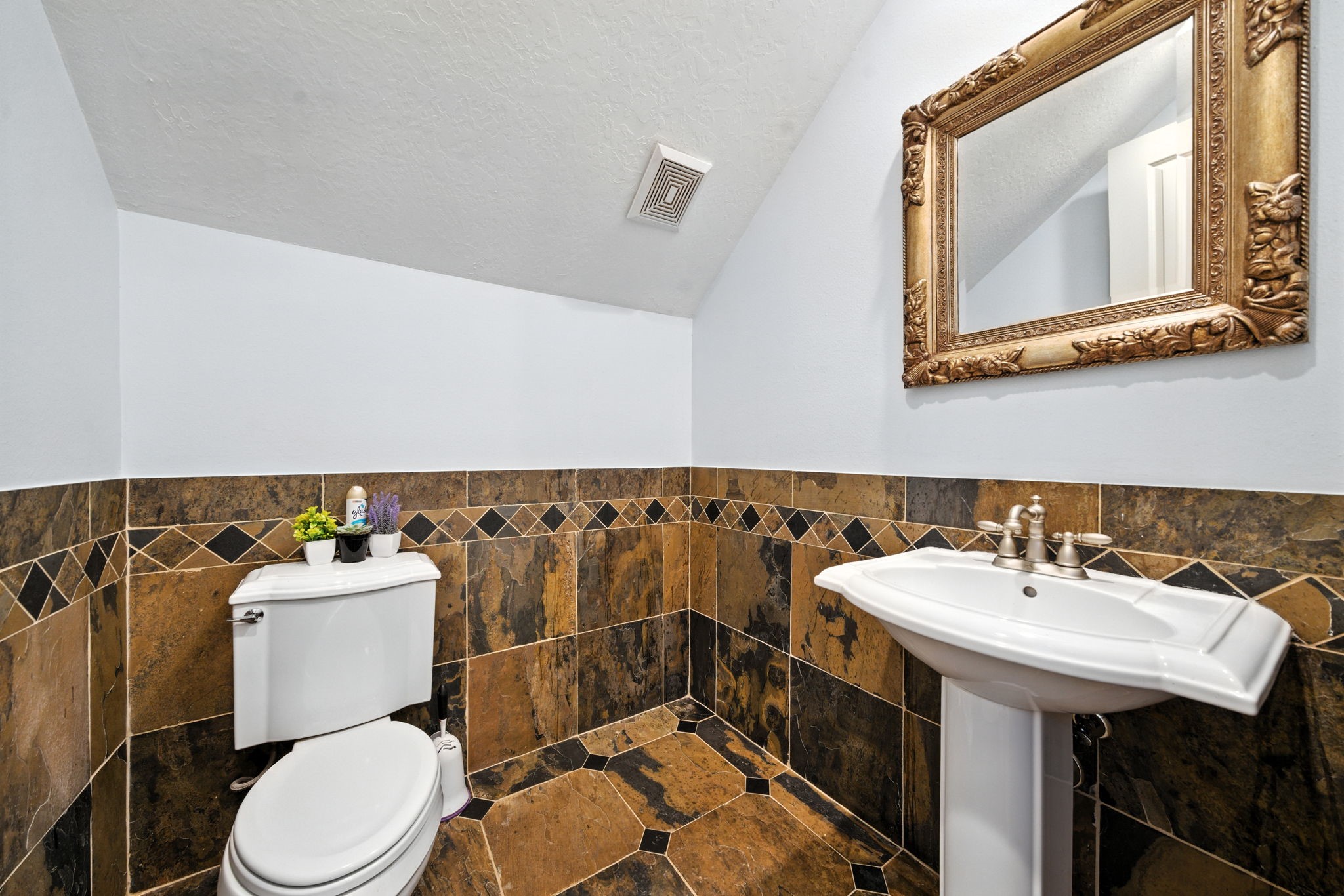 2714 Stuart Manor Houston, TX 77082 - Photo 40 of 49 The powder bath makes a statement with its bold slate tile and elegant design details. A pedestal sink, framed mirror, and warm tones create a sophisticated retreat for guests, combining both function and style.