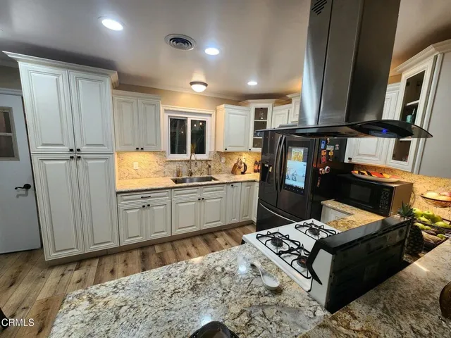 a kitchen with granite countertop a refrigerator stove and sink
