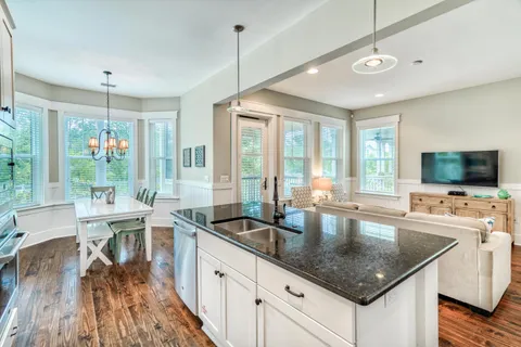 a kitchen with stainless steel appliances granite countertop a sink a stove and chairs with wooden floor