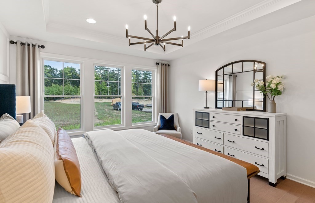 57 Sienna Circle, Unit 44 Upton, MA 01568 - Photo 16 of 21 a bedroom with a bed a chandelier and a large mirror on the dresser