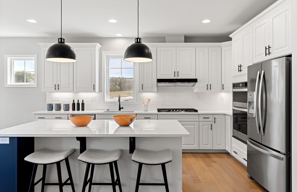 57 Sienna Circle, Unit 44 Upton, MA 01568 - Photo 5 of 21 a kitchen with stainless steel appliances granite countertop a sink a stove a refrigerator and white cabinets with wooden floor