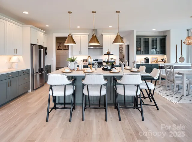 a dining room with stainless steel appliances kitchen island granite countertop a table chairs and a refrigerator