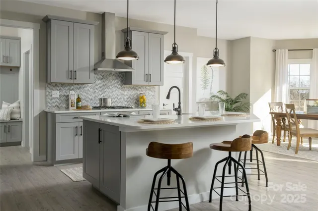 a kitchen with stainless steel appliances a sink a stove a dining table and chairs