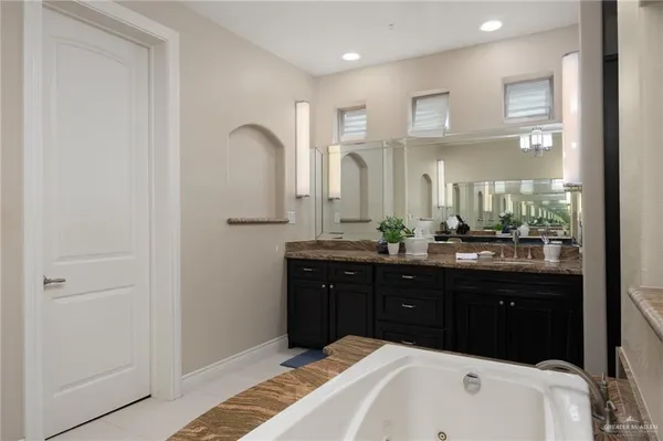 a en suite bathroom with a granite countertop sink and a mirror