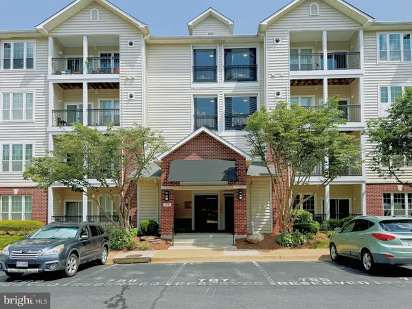 a front view of a residential apartment building with a yard and parking space