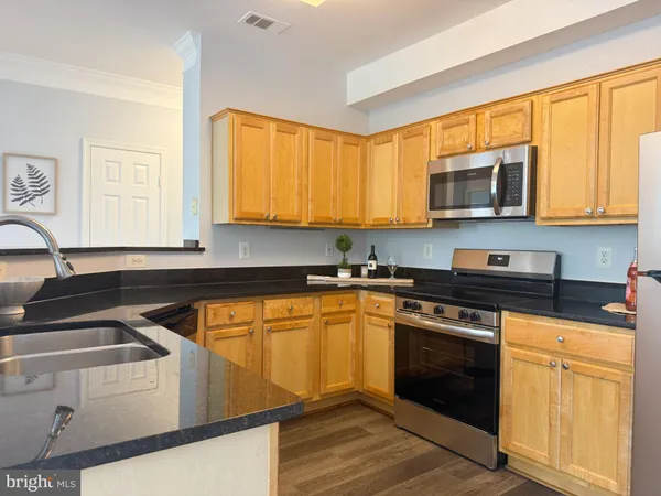 a kitchen with stainless steel appliances granite countertop a stove a sink and a microwave