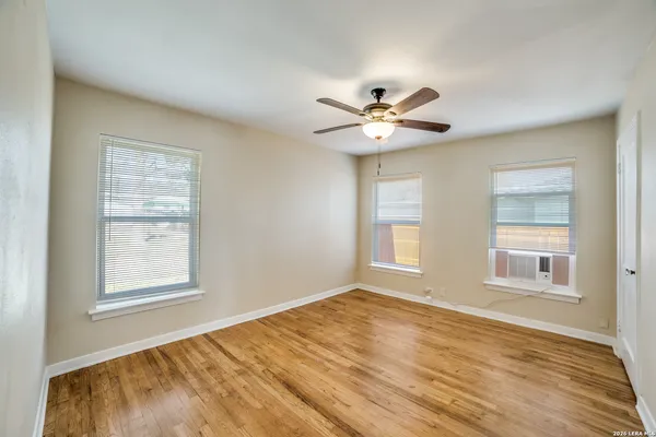 a view of an empty room with a window and wooden floor