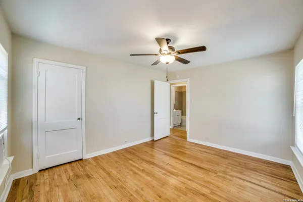 a view of a big room with wooden floor and a chandelier fan