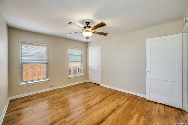 a view of empty room with wooden floor and fan