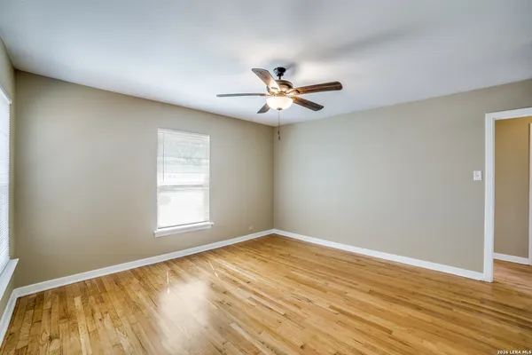 a view of empty room with wooden floor and fan