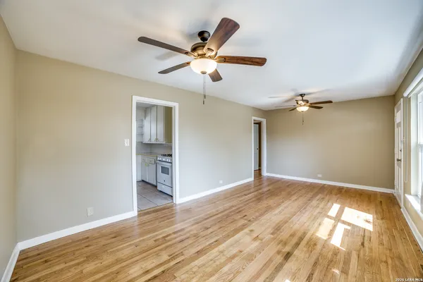 a view of empty room with wooden floor and fan