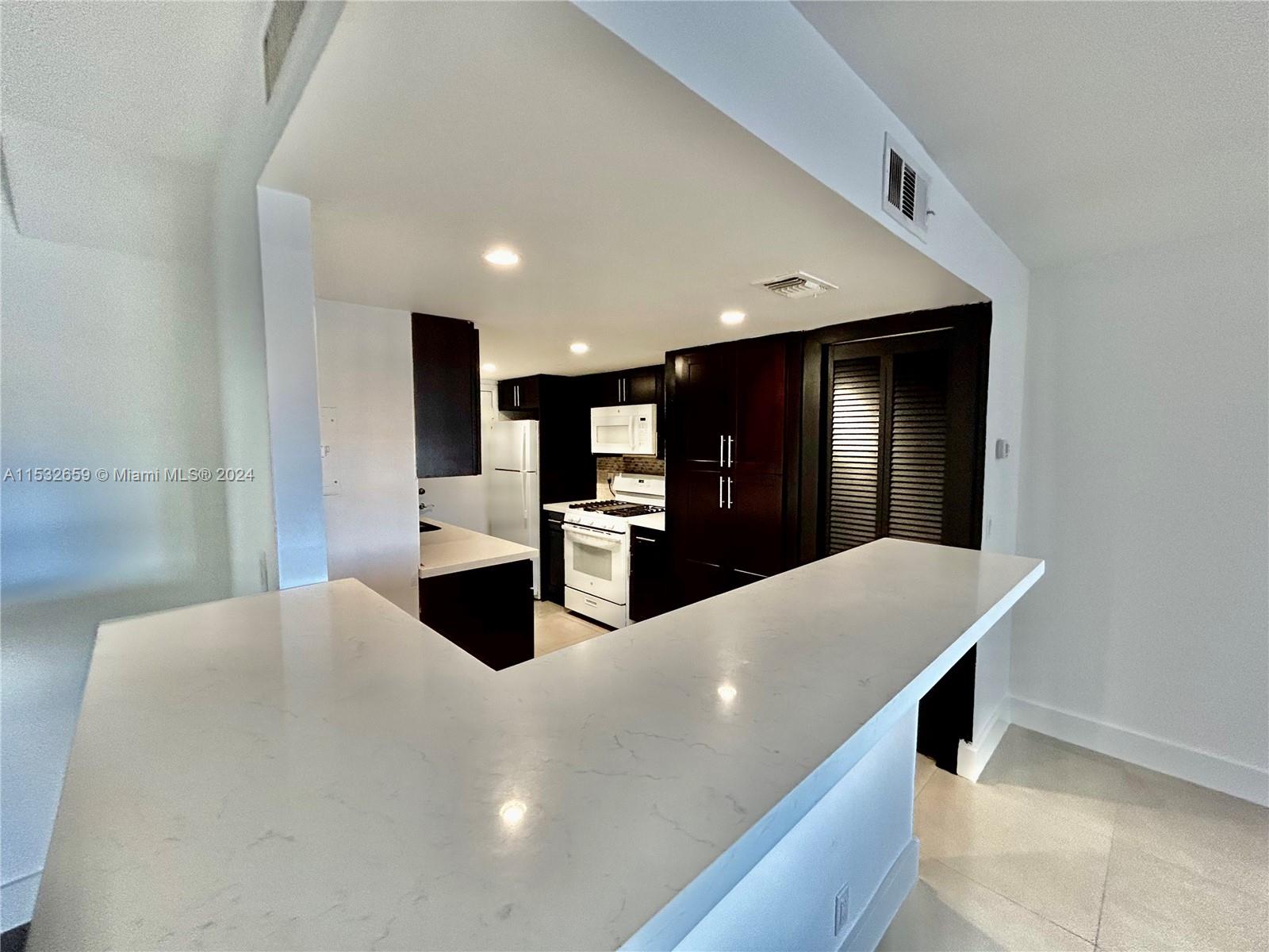 a large white kitchen with a large counter top stainless steel appliances and cabinets
