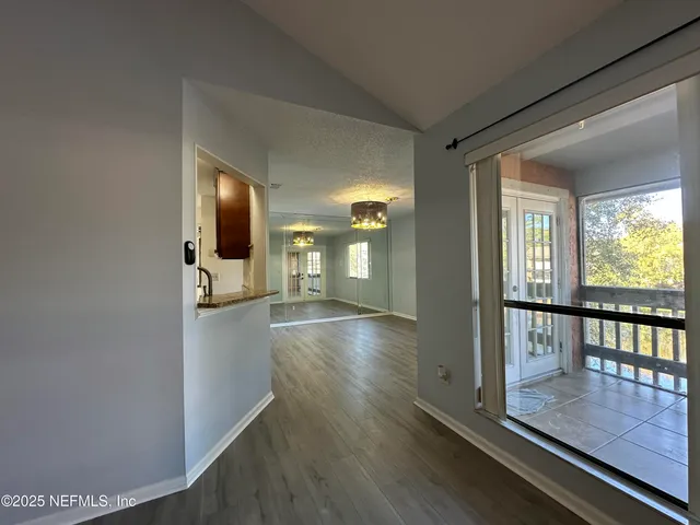 a view of an empty room with window and wooden floor