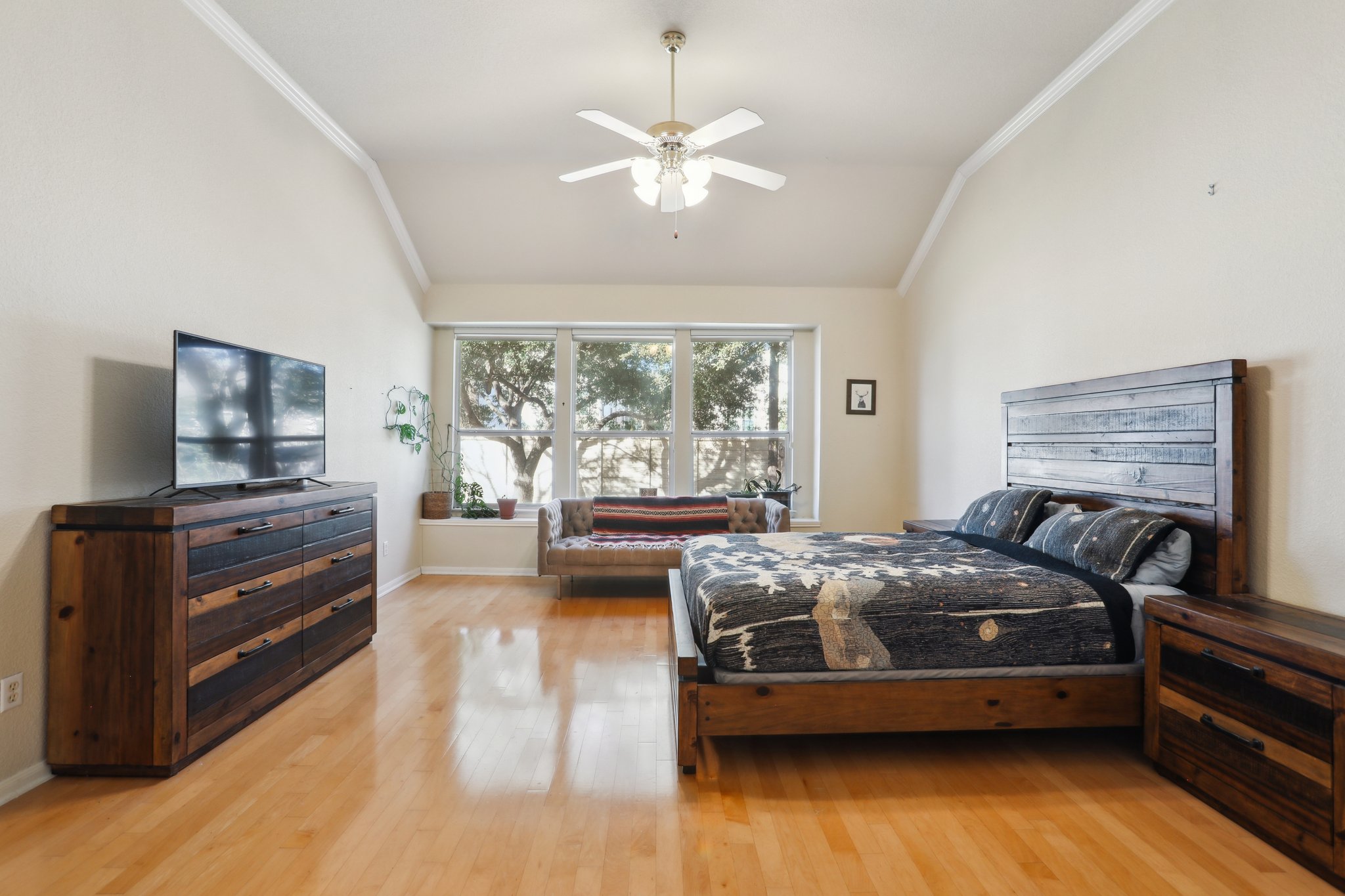 13541 Anarosa Loop Austin, TX 78727 - Photo 11 of 27 Spacious room featuring vaulted ceilings, crown molding, a ceiling fan with integrated lighting, wood-finish flooring, and large windows with a built-in window seat
