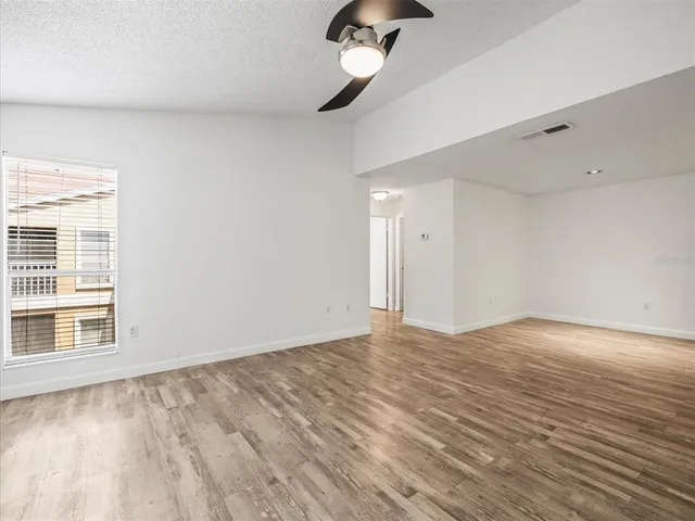 a view of an empty room with a window and wooden floor