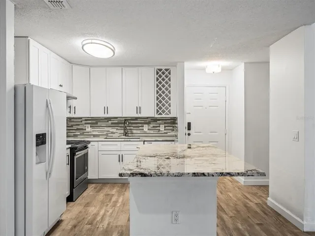 a kitchen with kitchen island granite countertop a sink stove and refrigerator