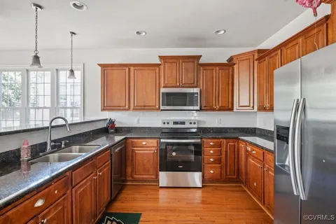 a kitchen with stainless steel appliances granite countertop a refrigerator and a stove top oven