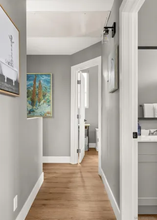 a view of a hallway with wooden floor and a living room
