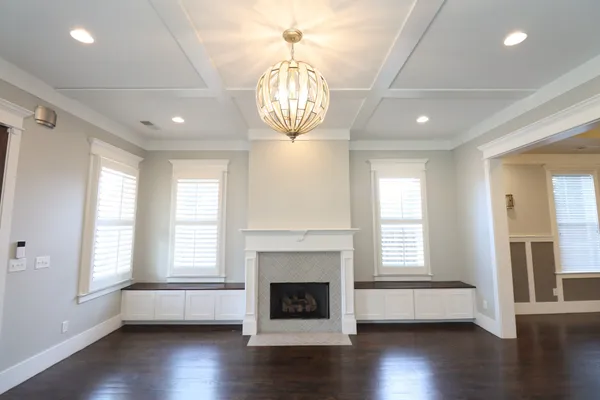 a view of an empty room with wooden floor fireplace and a window