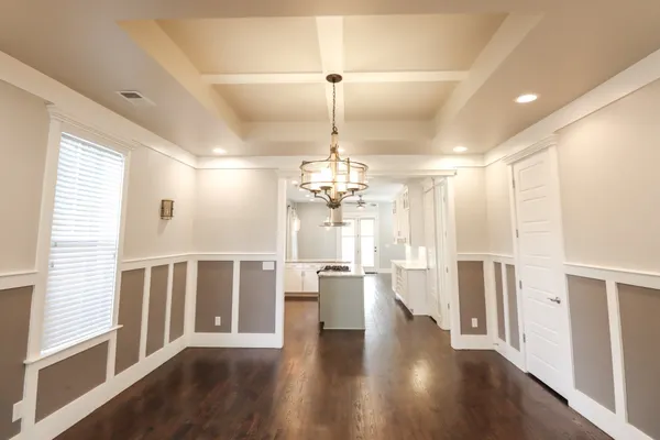 a view of a hallway with wooden floor and chandelier