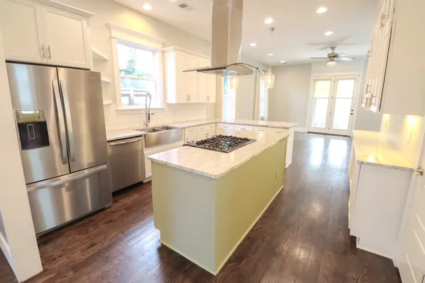 a kitchen with stainless steel appliances granite countertop a refrigerator a sink dishwasher a stove and a refrigerator with wooden floor