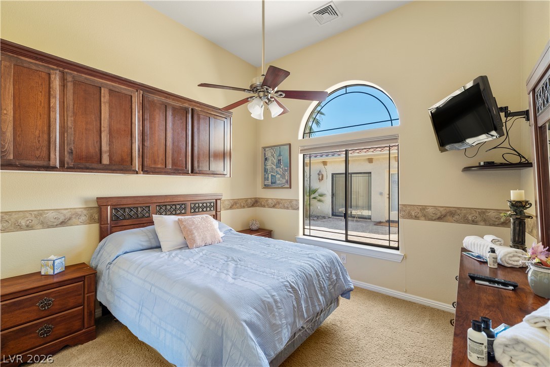 2181 Winery Road Pahrump, NV 89048 - Photo 19 of 52 Natural light floods this bedroom, highlighting the vaulted ceiling and views of a private courtyard. Wall cabinets for added storage along with a pot shelf over the closet.