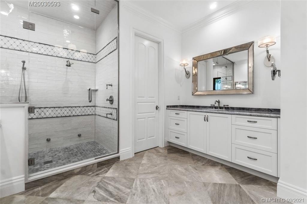 1904 Southeast Sailfish Point Boulevard Stuart, FL 34996 - Photo 26 of 72 a bathroom with a granite countertop sink mirror and shower