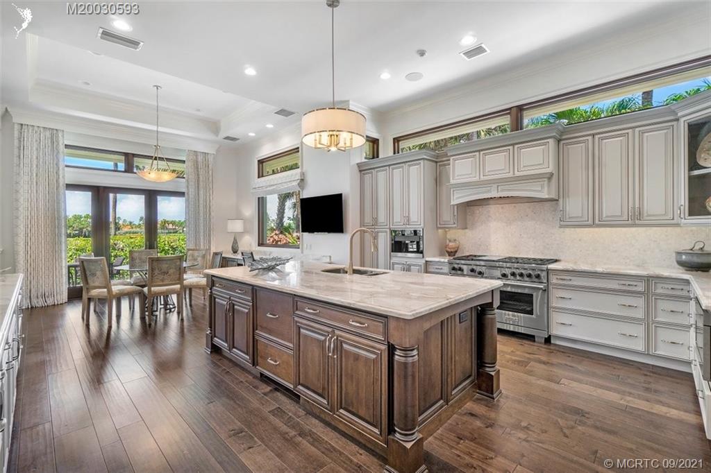 1904 Southeast Sailfish Point Boulevard Stuart, FL 34996 - Photo 7 of 72 a kitchen with kitchen island granite countertop a table chairs stove a sink dishwasher and cabinets with wooden floor