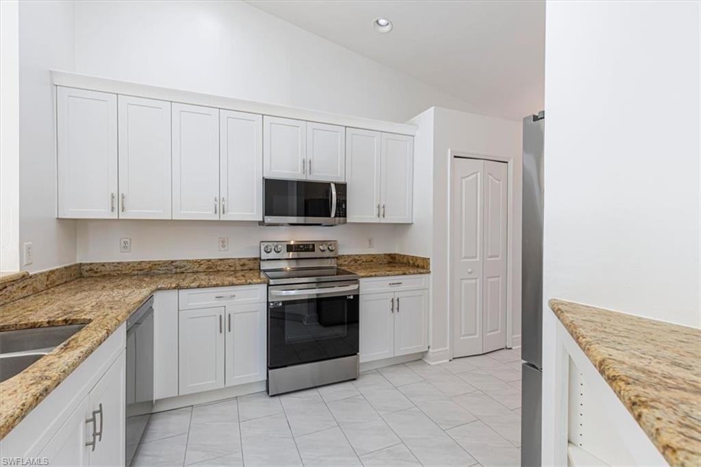5446 Whitten Drive, Unit 19 Naples, FL 34104 - Photo 13 of 24 a kitchen with stainless steel appliances granite countertop a stove top oven microwave and view kitchen