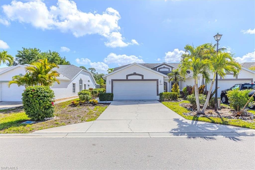 5446 Whitten Drive, Unit 19 Naples, FL 34104 - Photo 2 of 24 a front view of a house with a yard and garage