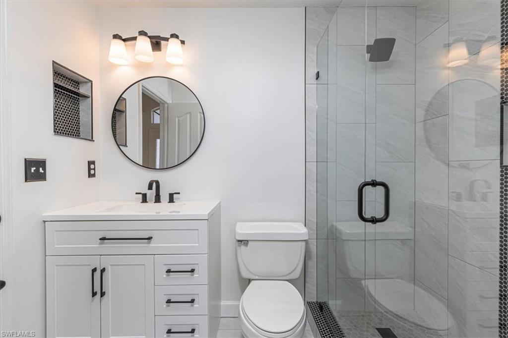 5446 Whitten Drive, Unit 19 Naples, FL 34104 - Photo 6 of 24 a bathroom with a toilet sink vanity granite and mirror