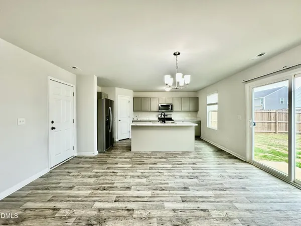 a view of a kitchen with kitchen island stainless steel appliances wooden floor and chandelier