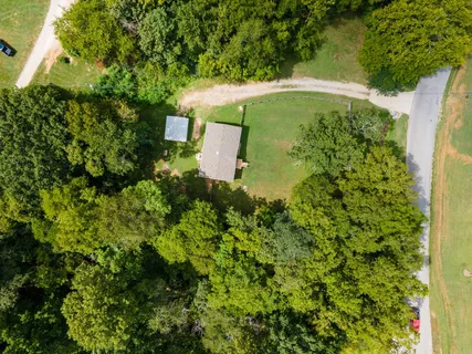 an aerial view of a house with a yard and large trees