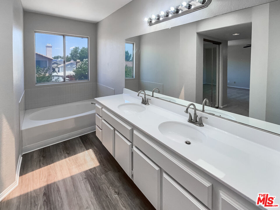 1615 East Kettering Street Lancaster, CA 93535 - Photo 4 of 15 a bathroom with a double vanity sink a mirror and a bathtub
