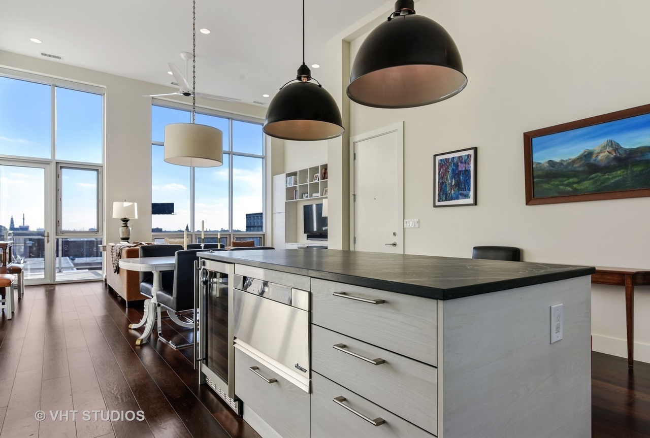 1132 West Adams Street, Unit PHE Chicago, IL 60607 - Photo 6 of 23 a kitchen with stainless steel appliances granite countertop a stove a sink a dining table and chairs with wooden floor