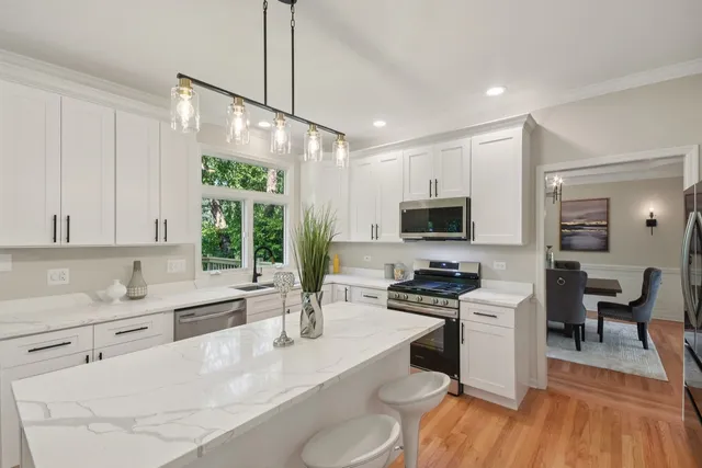 a kitchen with stainless steel appliances a stove a sink a microwave a dining table and chairs