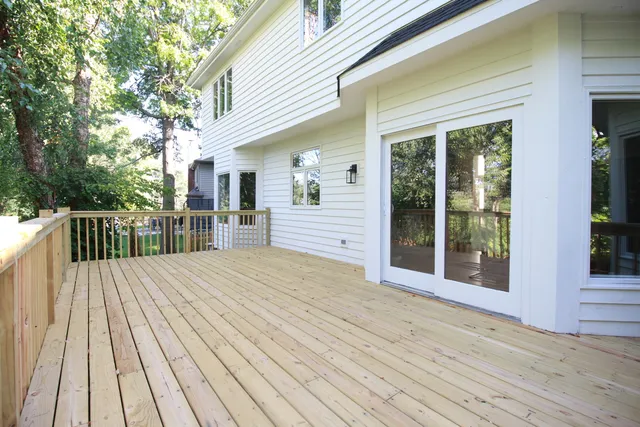a balcony with wooden floor and trees in the back