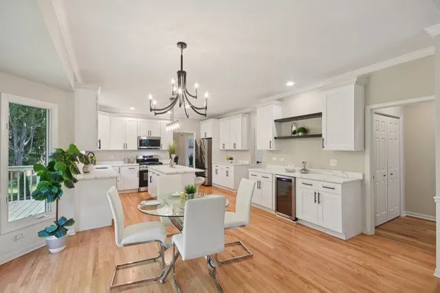 a view of a dining room and livingroom with furniture wooden floor a chandelier