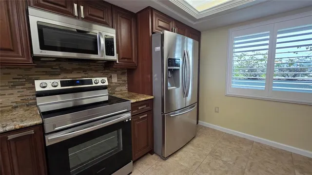 a kitchen with granite countertop cabinets stainless steel appliances and a window