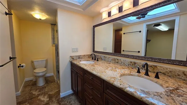 a bathroom with a granite countertop double vanity sink and a mirror