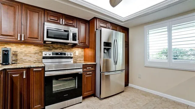 a kitchen with stainless steel appliances granite countertop a refrigerator microwave and sink