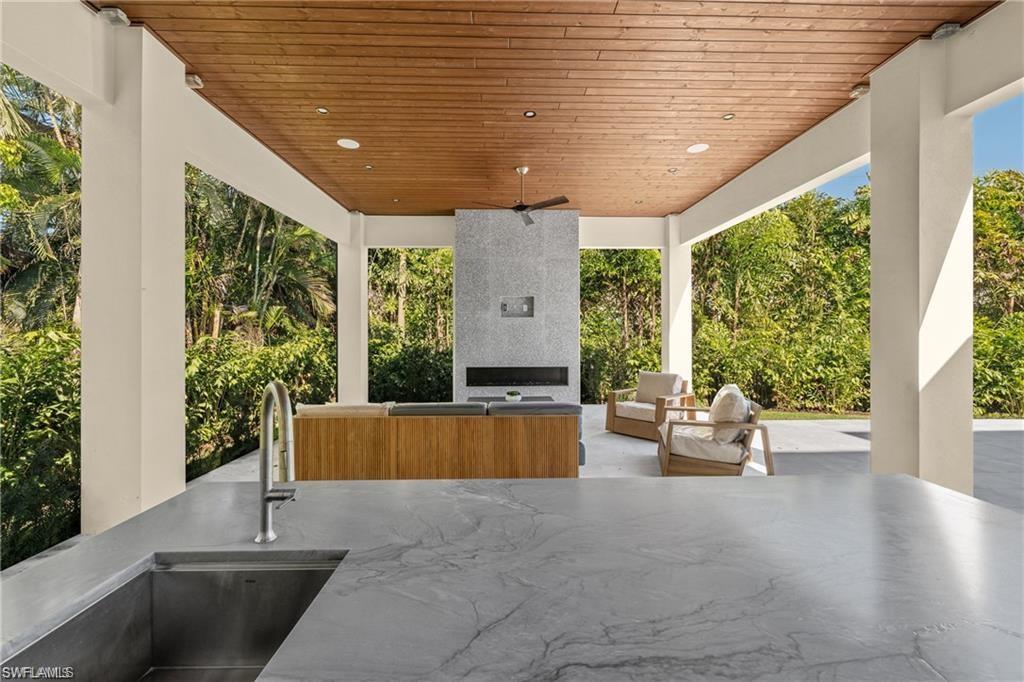 1800 Crayton Road Naples, FL 34102 - Photo 27 of 32 View of patio / terrace featuring an outdoor living space with a fireplace and view of scattered trees