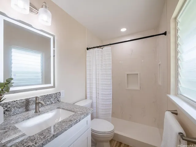 a bathroom with a granite countertop sink toilet and shower