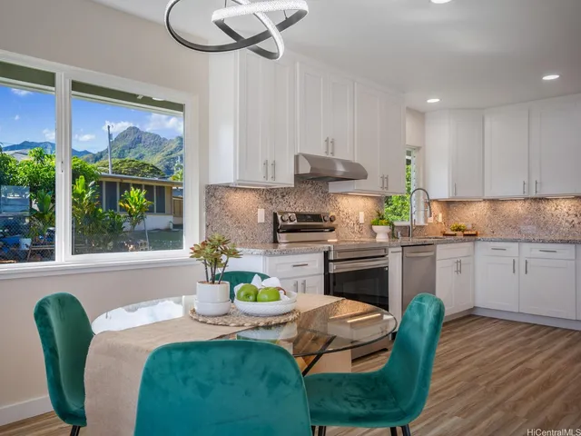 a kitchen with stainless steel appliances granite countertop a stove a refrigerator a sink a dining table and chairs with wooden floor