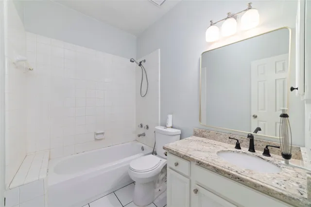 a bathroom with a granite countertop sink a toilet and bathtub